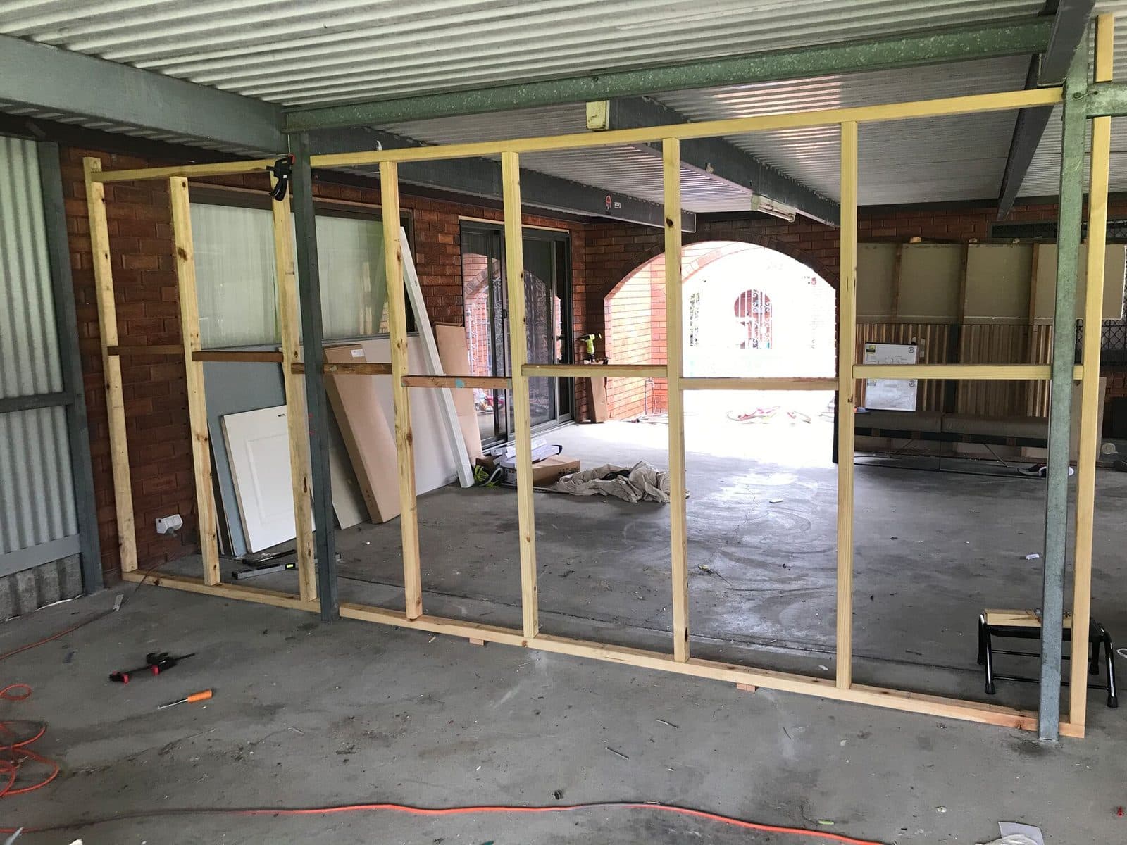 New timber stud wall framed between steel posts under a carport