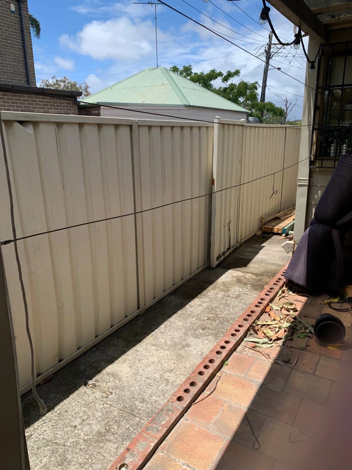 Plain Colorbond fence along a brick-paved patio in Mascot before the privacy screens